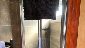 Cabina de ducha con paredes de vidrio y un perchero a la izquierda.