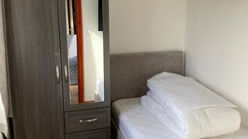 Un dormitorio con cama, armario y espejo.