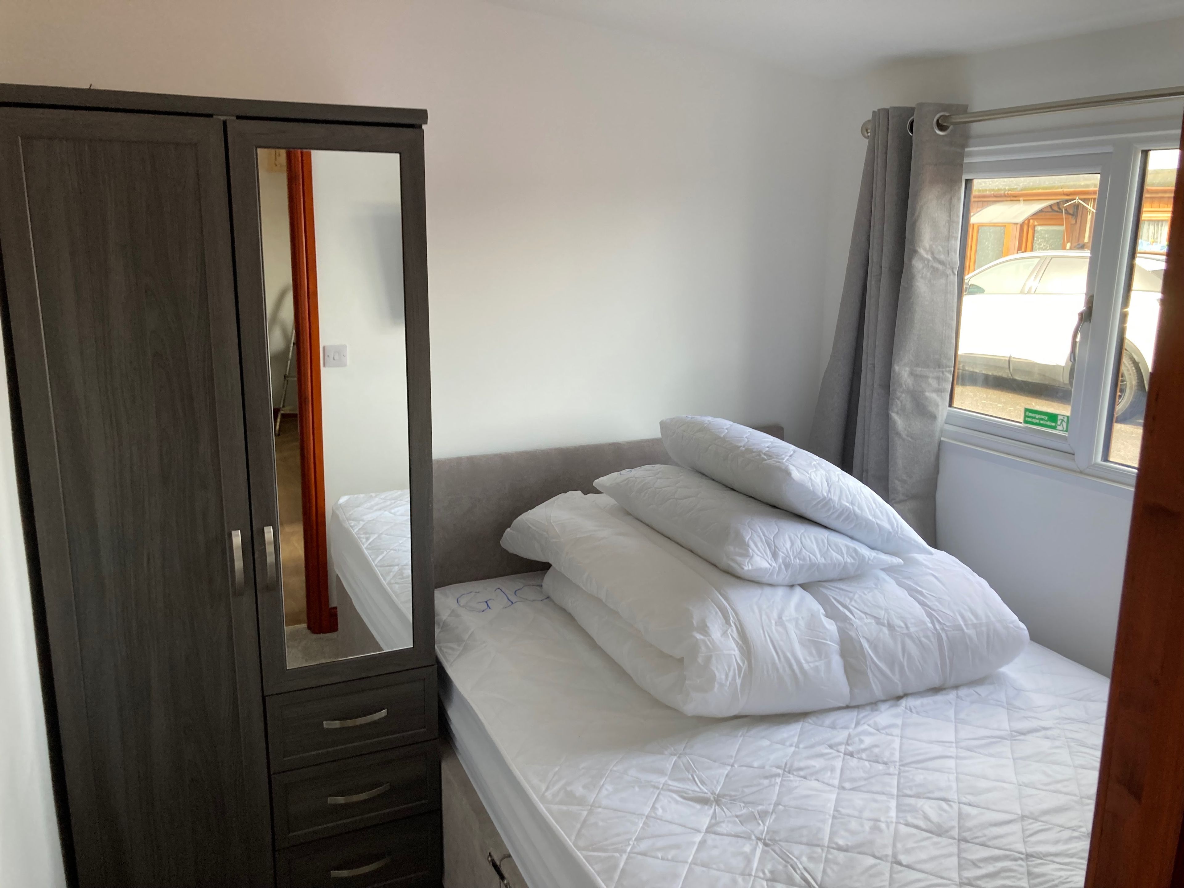 A bedroom with a bed, a wardrobe, and a window.