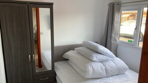 Un dormitorio con cama, armario y ventana.