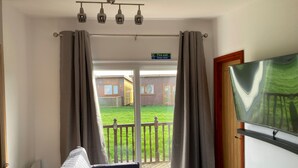 Una habitación con cama, televisión y vista a un patio cercado.