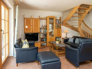 A living room with a sofa set, a television, a bookshelf, and a wooden staircase. - 10/t6 Holiday Home Park \"freesenbruch\" (Zingst)