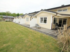 A row of single-story cabins with attached porches, each with a small patio area and a single lounge chair. - Lapwing at Susanne-fischer-weg 31 (Wyk auf Foehr)