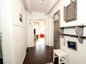 Ein Flur mit weißen Wänden, einer Holztür, einer Bank und einem Regal mit einer Kreidetafel.