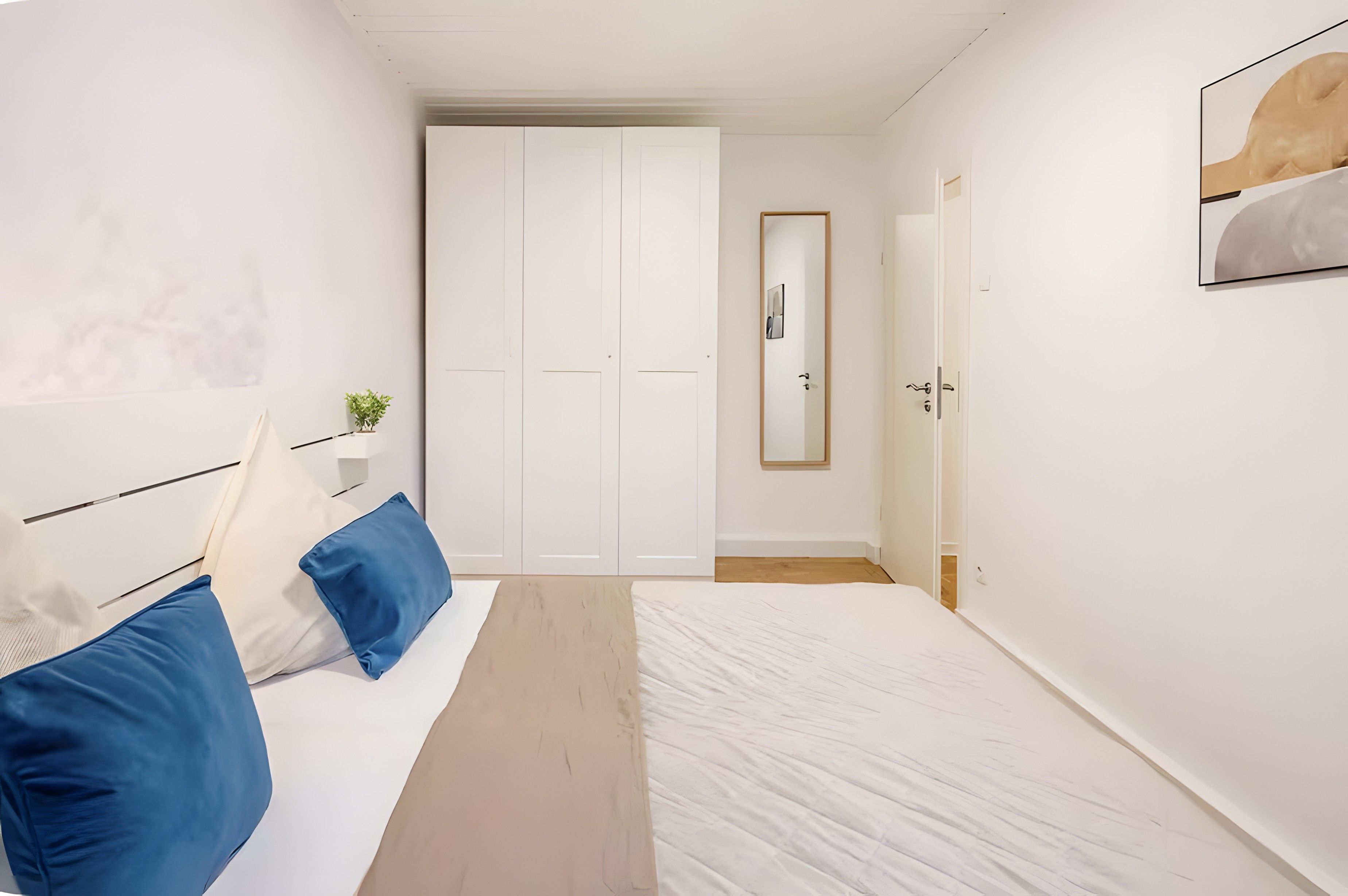 Une chambre à coucher avec un lit, une table de chevet, un miroir et une armoire.