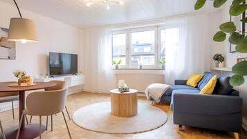 Un salon moderne avec un canapé, une table à manger et un téléviseur.