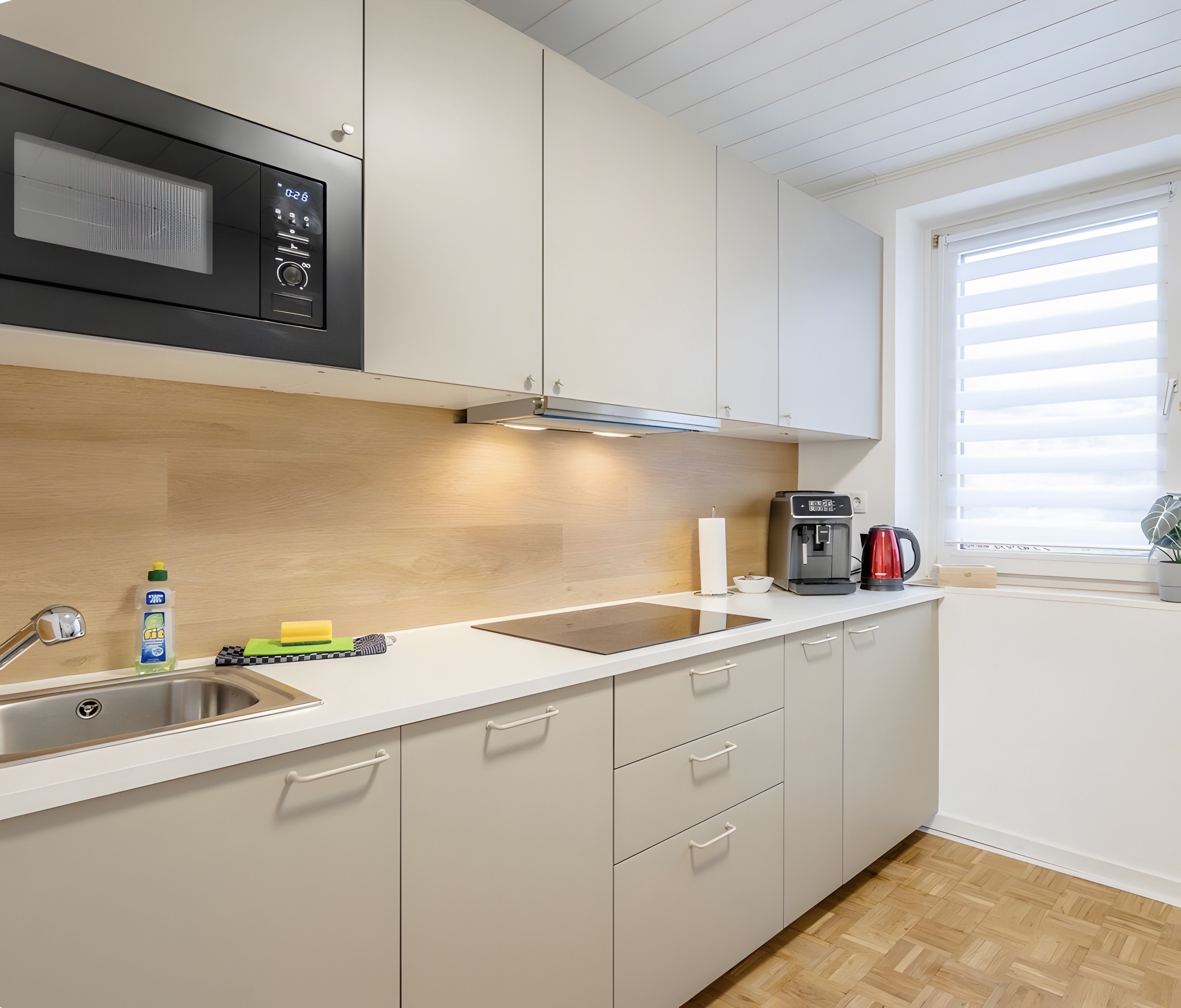 Una cocina moderna con microondas, cafetera y ventana con persianas.