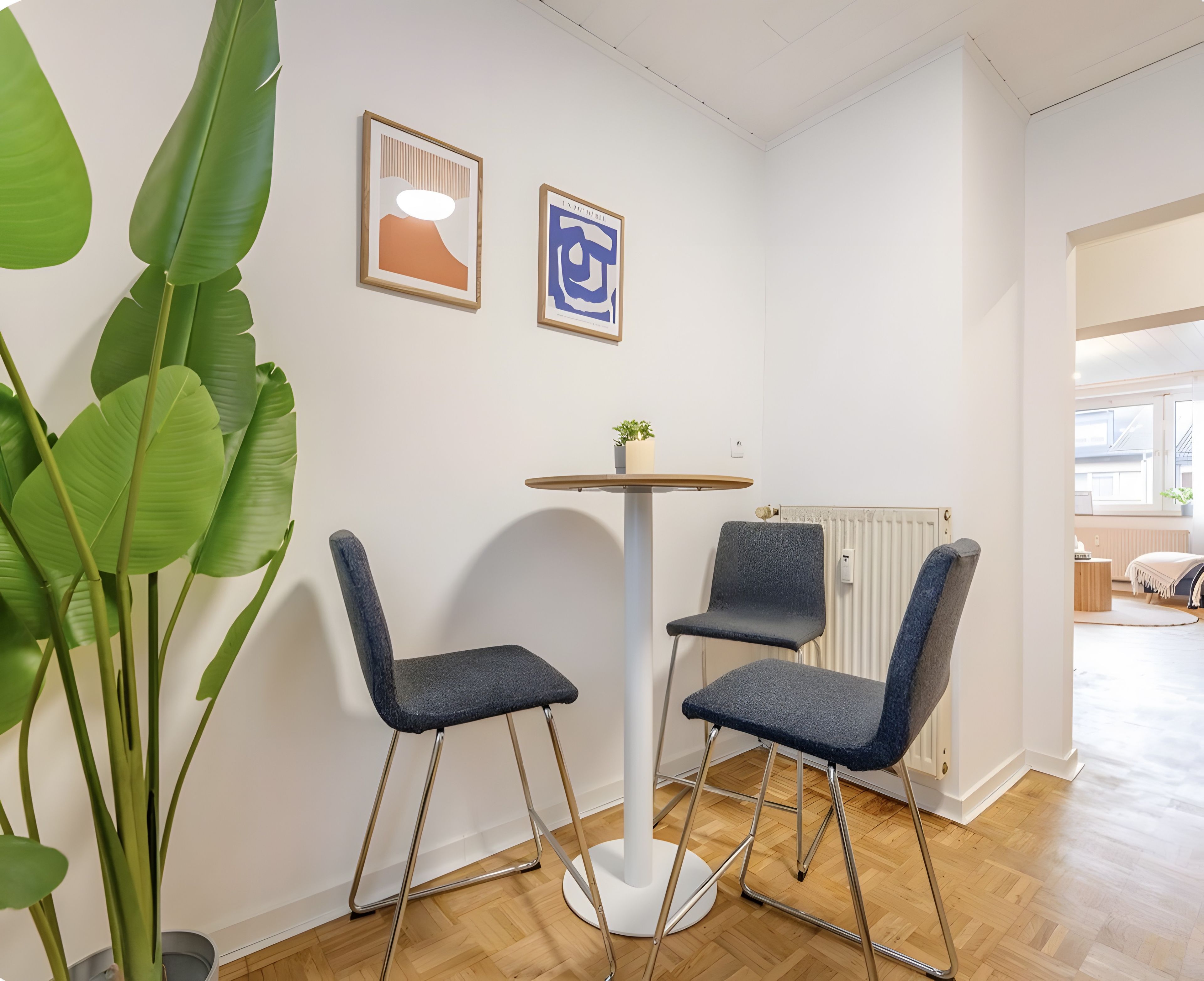 A modern interior with a round table, two chairs, and a potted plant.