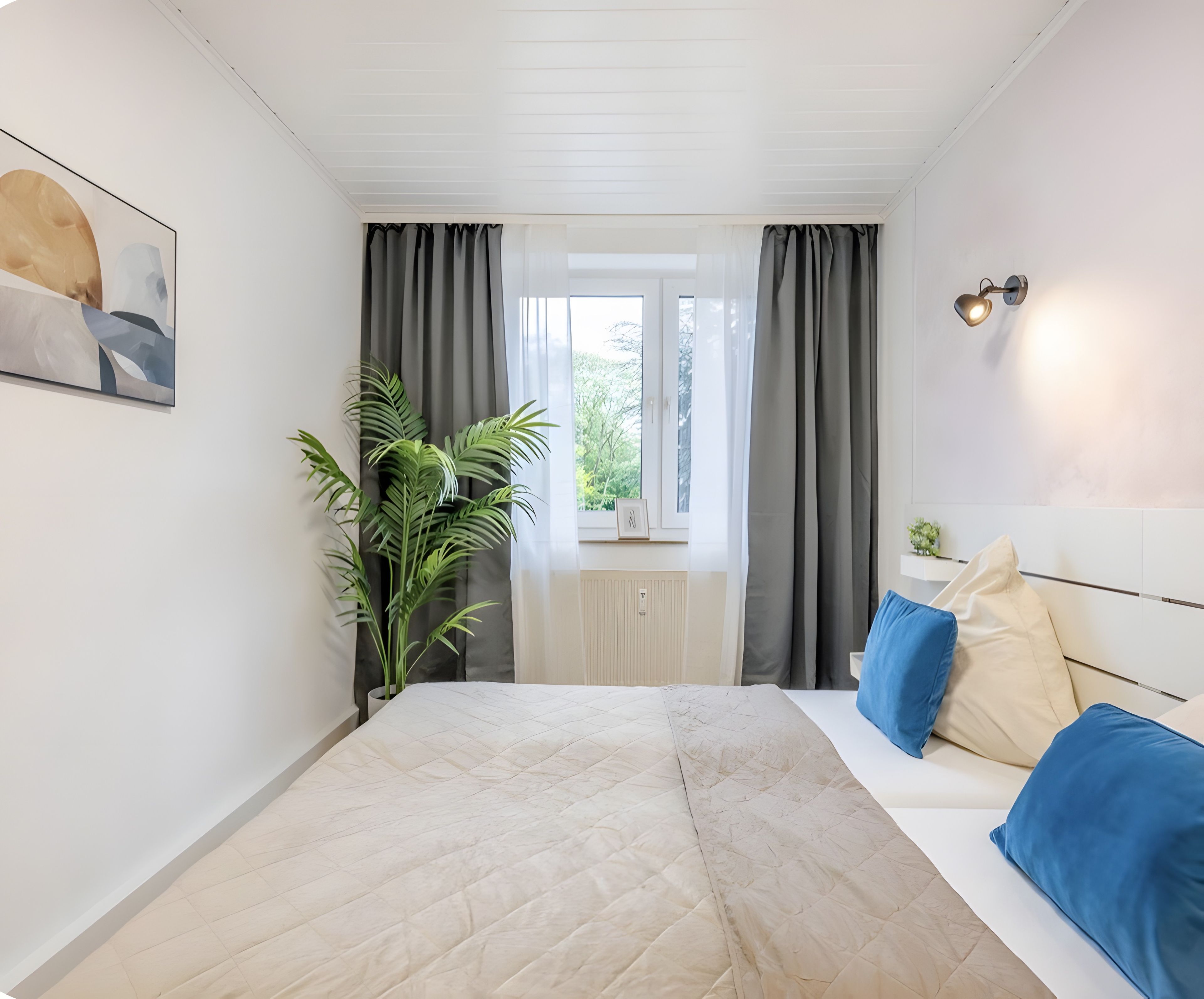 Ein Schlafzimmer mit einem Bett, einem Fenster mit Vorhängen, einer Topfpflanze und einer Wandleuchte.