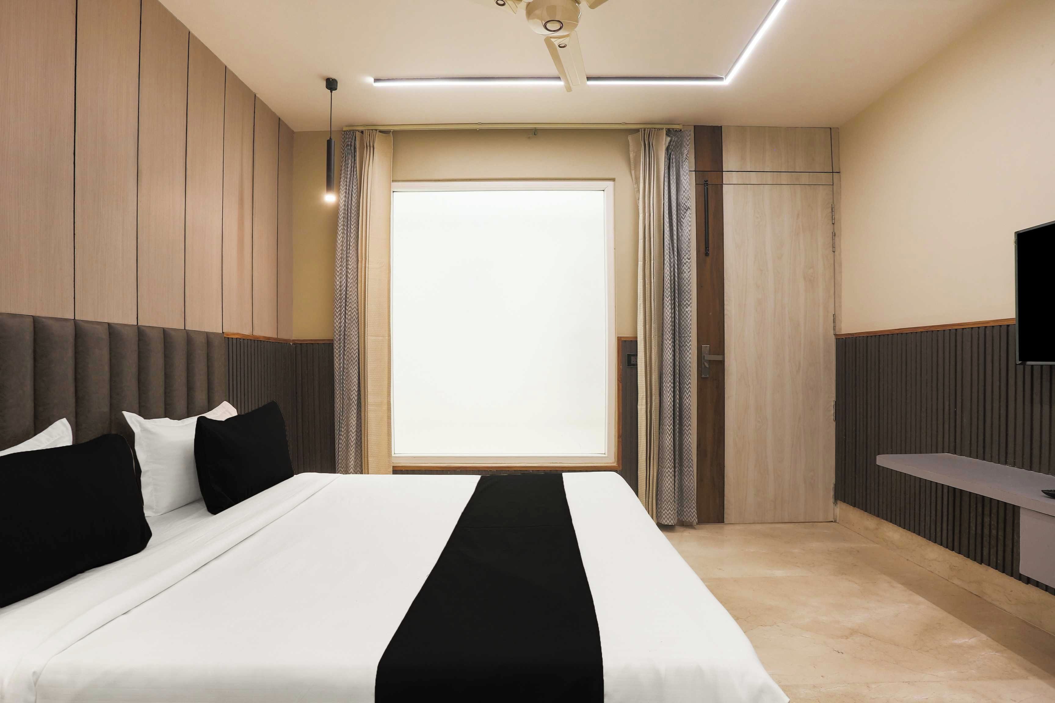 A modern hotel room with a large bed, a flat-screen TV, and a view of the outdoors.