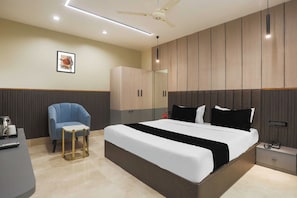 Un dormitorio moderno con una cama grande, un sillón azul, una mesita y un armario.