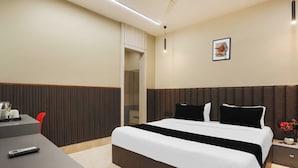 Habitació d'hotel amb llit, taulella de nit i escriptori amb cadira.