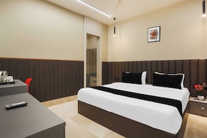 Habitación de hotel con cama, mesita de noche y escritorio con silla.