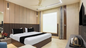 Habitació d'hotel moderna amb un llit gran, una taula amb una paperera i una televisió.