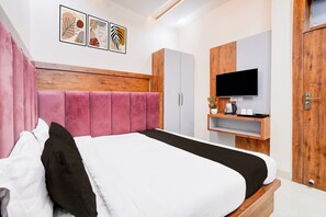 Quarto moderno com cama grande, armário, televisão e obras de arte na parede.
