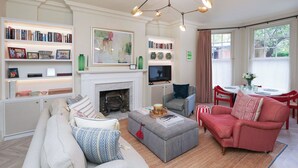 Una sala de estar con chimenea, estanterías, televisor y comedor con mesa y sillas.