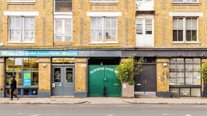 Un edificio con escaparate que dice 'TaxAssist Accountants' y una puerta verde con el rótulo 'Playhouse Court'.