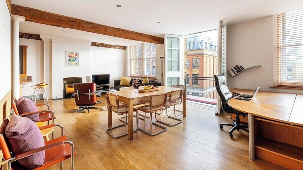 Amplia sala de estar con mesa de comedor de madera, asientos cómodos, chimenea y vista a la ciudad a través de grandes ventanales.