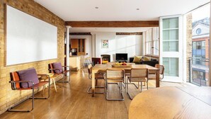 Un amplio espacio de sala con una pizarra grande, mobiliario de madera y vistas a la ciudad.