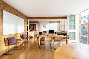 A spacious living area with a large whiteboard, wooden furniture, and a view of the city.