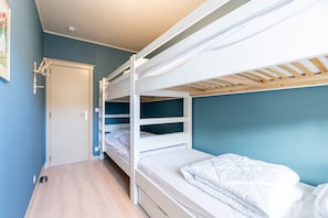 Ein Schlafzimmer mit Etagenbett, Tür und kleinem Fenster.