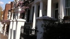 Una hilera de casas adosadas con fachadas blancas y barandales negros.