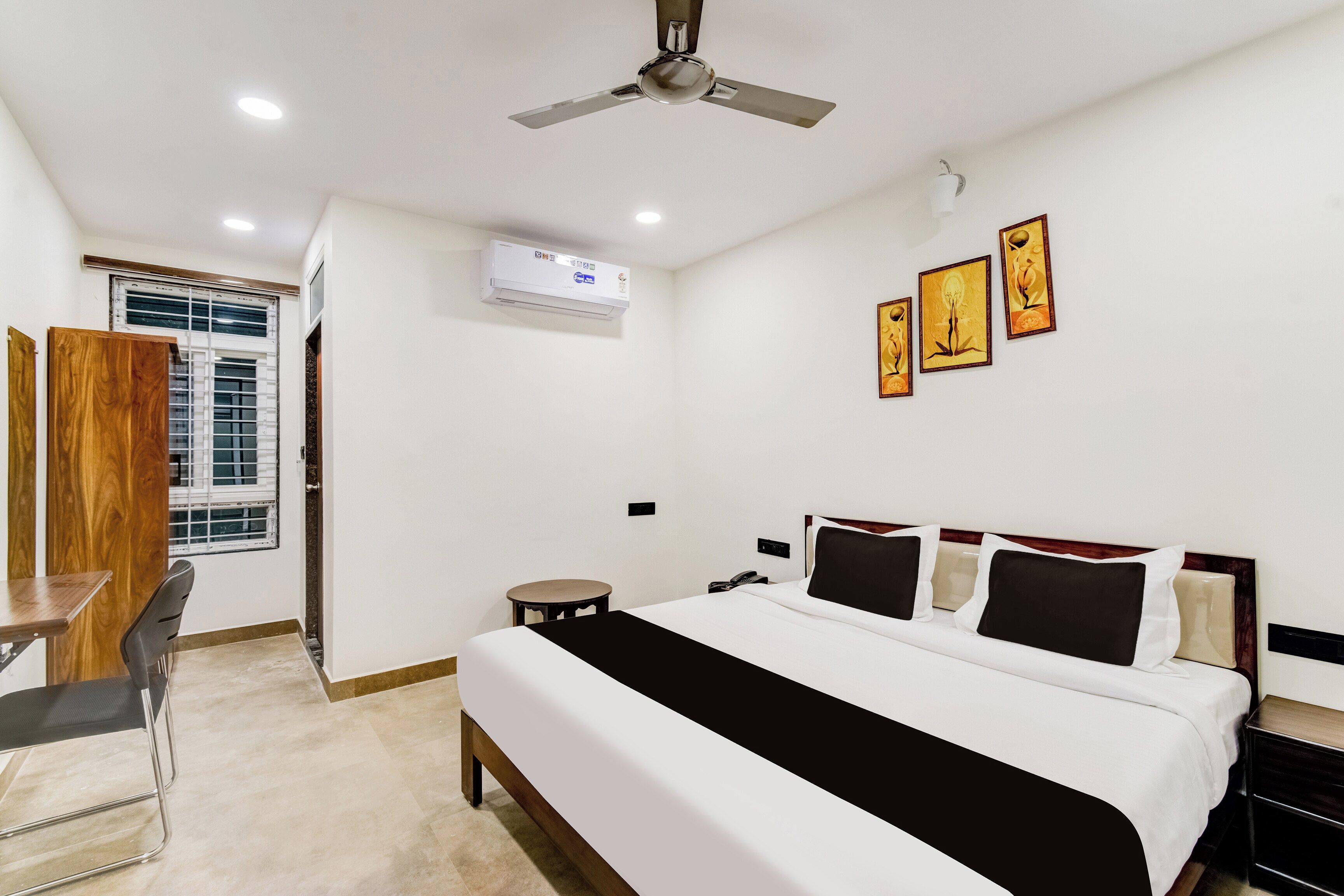 Une chambre d’hôtel avec un lit, une table de chevet, une chaise et un ventilateur de plafond.