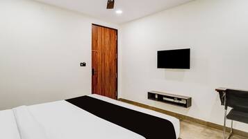 A bedroom with a bed, a television mounted on the wall, and a desk with a chair.
