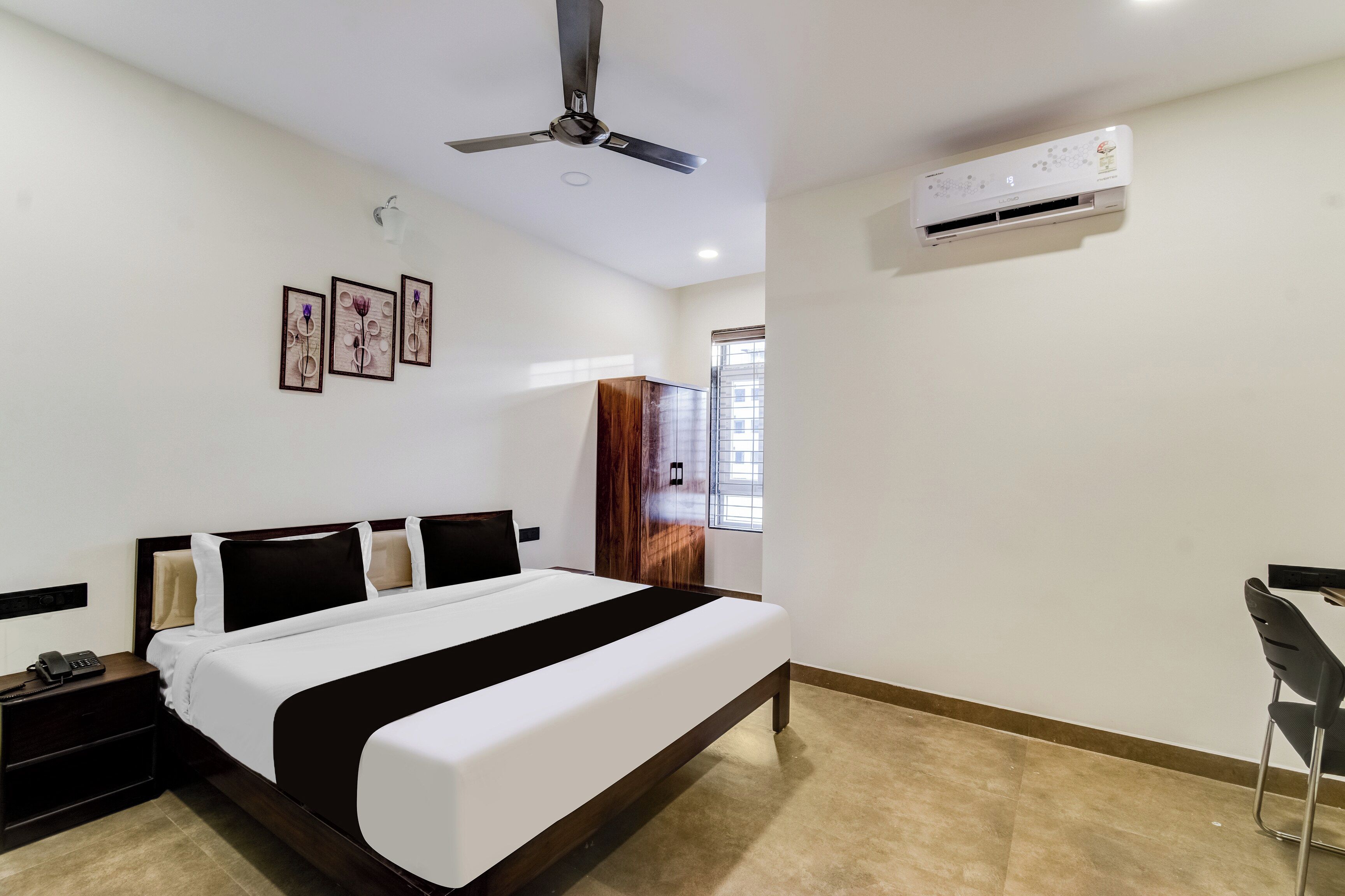 A hotel room with a bed, bedside table, and a desk with a chair.