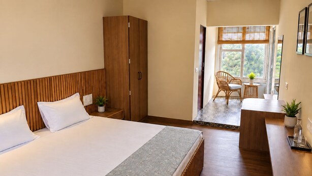 Een hotelkamer met een groot bed, een houten garderobe en een zithoek met een tafel en stoelen.