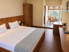 Una habitación de hotel con una cama grande, un armario de madera y una pequeña zona de estar con mesa y sillas.