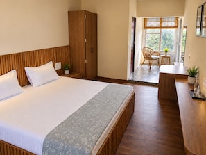 Une chambre d’hôtel avec un grand lit, une armoire en bois et un petit coin salon avec une table et des chaises.
