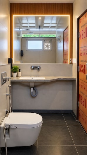 Uma casa de banho moderna com sanita, lavatório e chuveiro.
