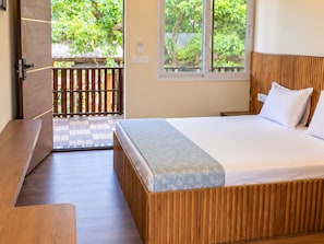 Quarto com cama de madeira, um banco e vista para um deck de madeira e vegetação lá fora.