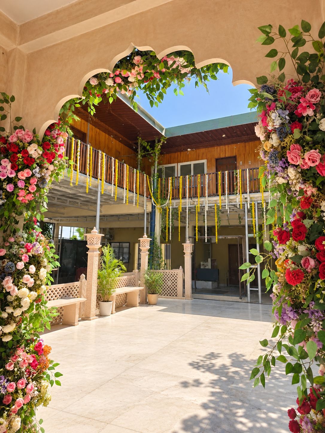 Un espace extérieur doté d’un coin salon abrité, d’une clôture en bois et d’une arche ornée de fleurs.