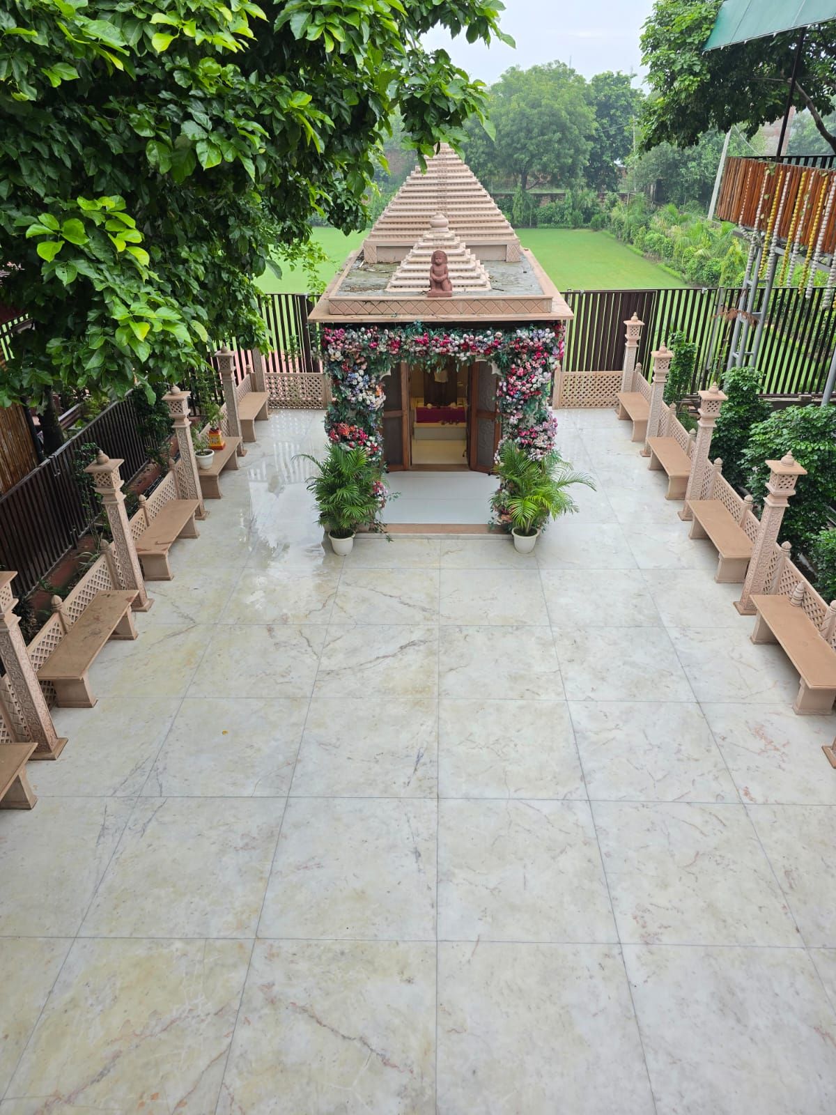 A temple-like structure with a tiered roof, surrounded by a garden with benches and potted plants.