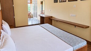 Een slaapkamer met een bed, een houten bankje en uitzicht op buiten.