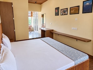 Quarto com cama, um banco de madeira e vista para o exterior.