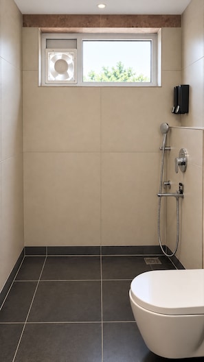 Une salle de bain moderne équipée de toilettes, d’une douche avec un pommeau de douche amovible et d’une fenêtre située au-dessus de la douche.