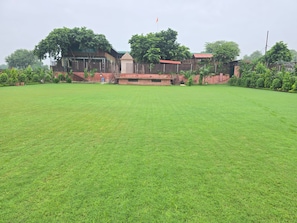 Une vaste étendue d’herbe, à ciel ouvert, avec un bâtiment visible au loin.