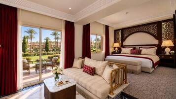 A hotel room with a balcony, a bed, a sofa, and a coffee table.