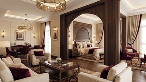 Una habitación de hotel con una cama grande, una zona de estar con sofá y sillones, un comedor y un arco decorativo.