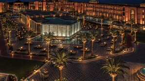 Un gran hotel con varias edificaciones, un área de piscina central y mobiliario exterior.