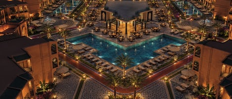 A large hotel with multiple swimming pools, outdoor seating areas, and a central courtyard.