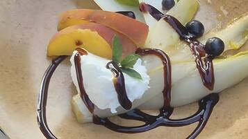 Ein Dessertteller mit einer Kugel Eis, Fruchtstücken und Schokoladendrizzle.