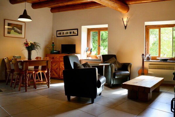 A living room with a dining area, a fireplace, and large windows.
