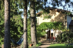 A house with a garden, a hammock, and a patio with chairs.