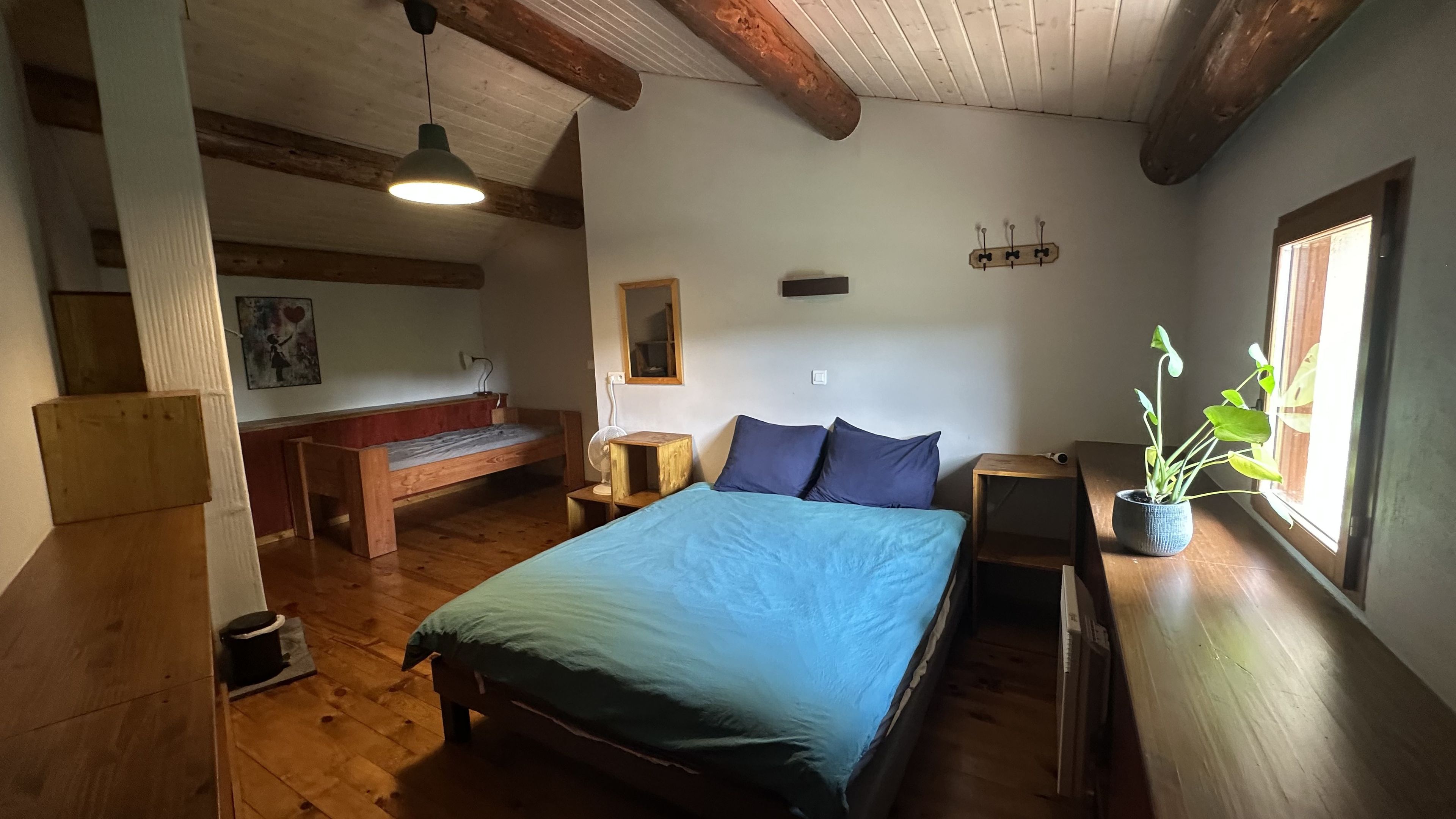 Une chambre confortable avec un lit, un banc, une table de chevet et une plante en pot.