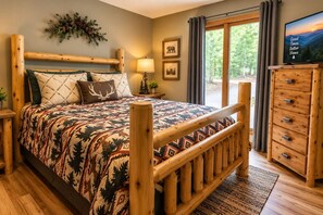 Una habitación con una cama que tiene un cabecero de madera, una mesita de noche con una lámpara, un aparador con cajones y un televisor sobre un mueble de madera.