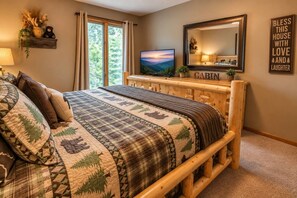 A bedroom with a wooden bed, a television, a mirror, and a sign on the wall. - Wandering Bear | Hot Tub + Game Room | Near PF (Pigeon Forge)